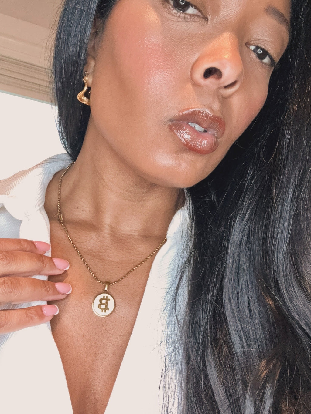 Woman wearing a gold necklace with a Bitcoin pendant.